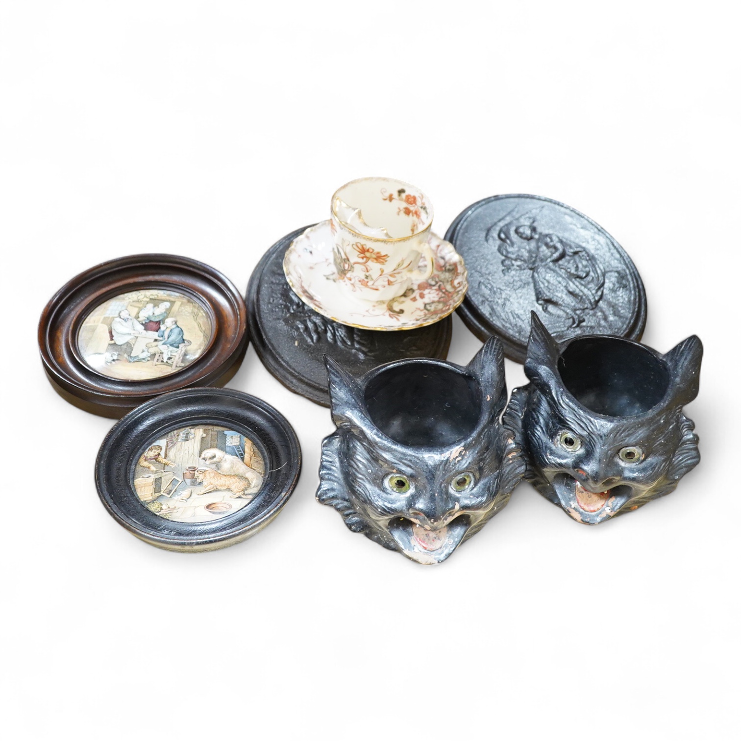 Two framed pot lids, two oval figural plaques,a moustache cup and saucer, two Bretby cats, framed print and mixed nut crackers cutlery etc